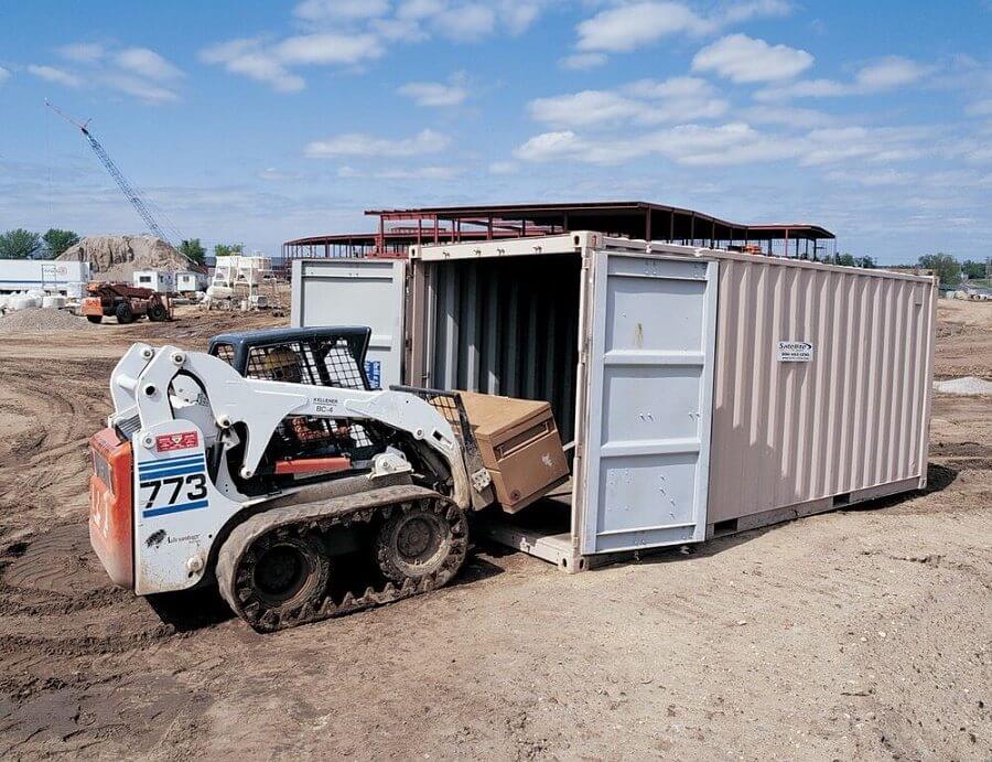 20 foot conex storage container, double doors, small construction vehicle driving inside it